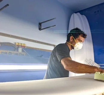 Craftsman shaping a surfboard in the workshop