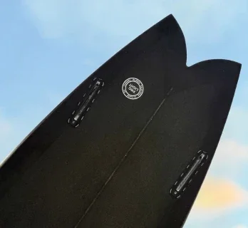Shaper sanding a surfboard with dust in the air